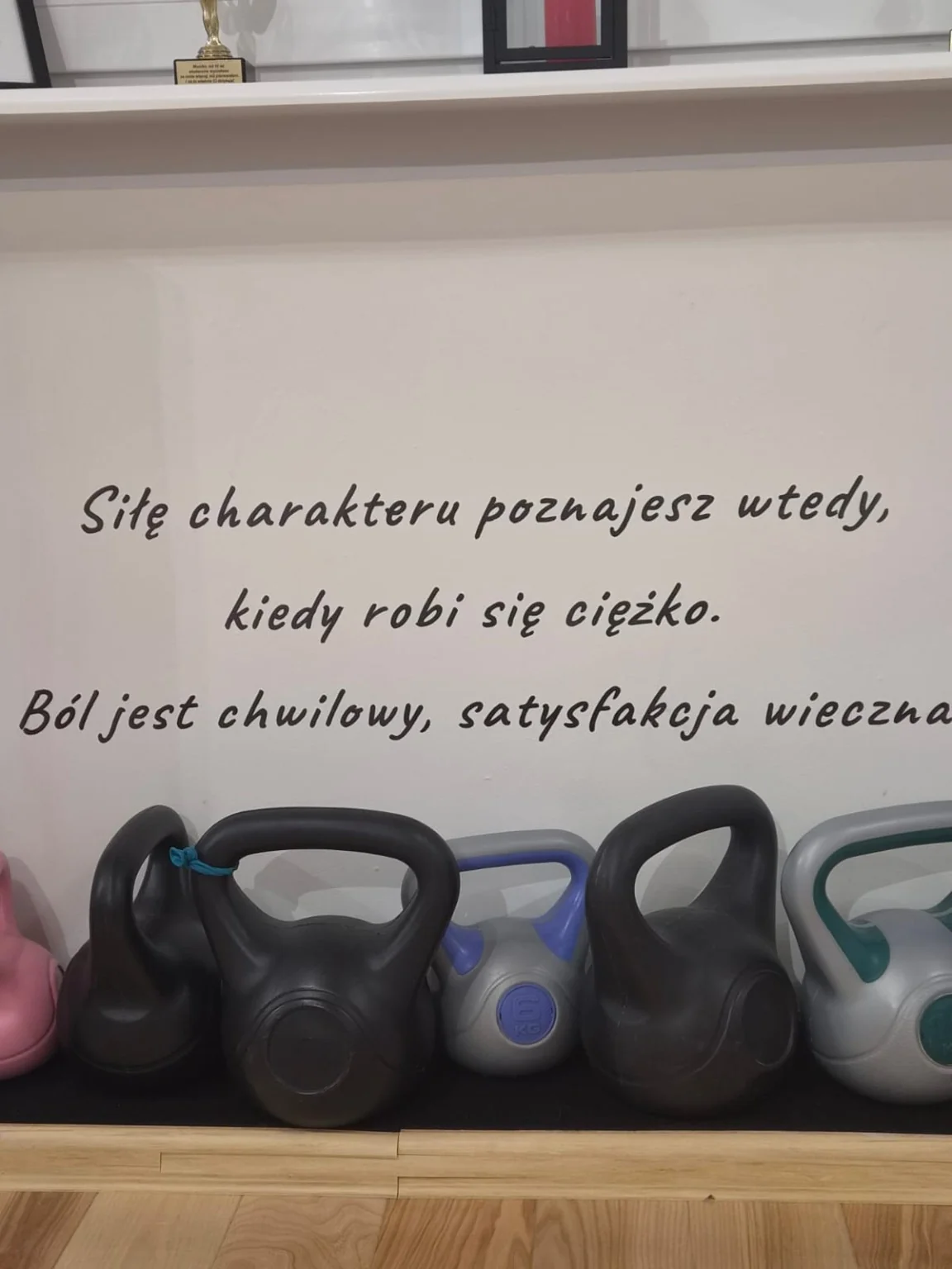 Kinesis Studio — ciężarki treningowe i napis motywacyjny